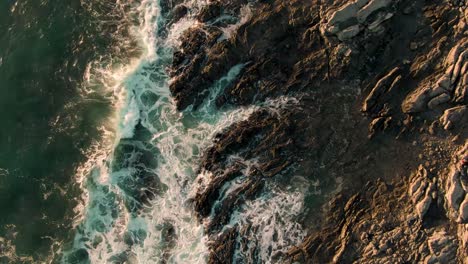drone z góry na dół żuraw strzał łamiących się fal na skalistej plaży kostaryki w zachodzie słońca