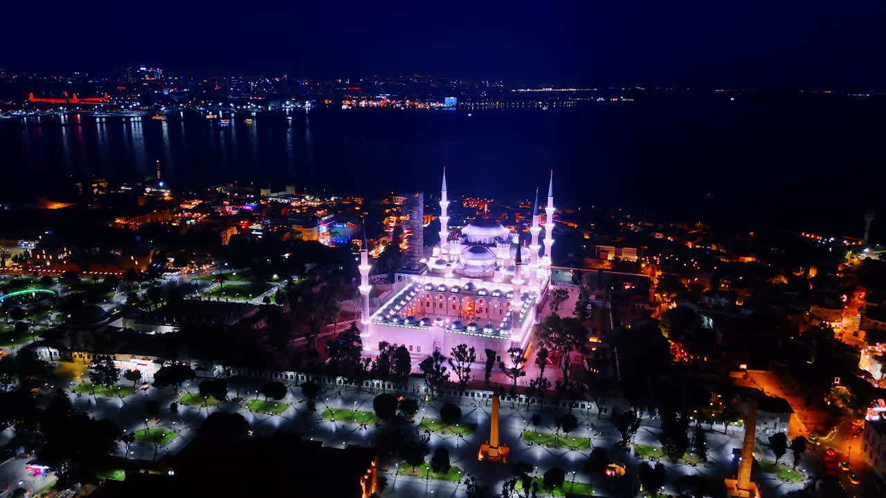 Fantastically illuminated mosque in the night scenery of the city. Drone flight over the beautiful panorama of Kemer, Turkey