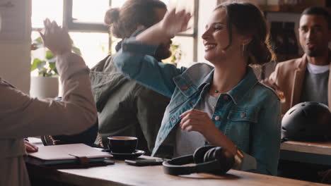 Hermosa-Mujer-Charlando-Con-Un-Amigo-En-El-Café-Riéndose-De-Una-Divertida-Conversación-Chocando-Los-Cinco-Disfrutando-De-Pasar-El-Rato-En-Un-Concurrido-Restaurante