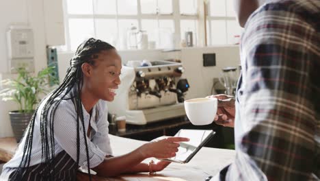 felices mujeres y hombres afroamericanos dueños de cafeterías hablando y usando tableta, cámara lenta