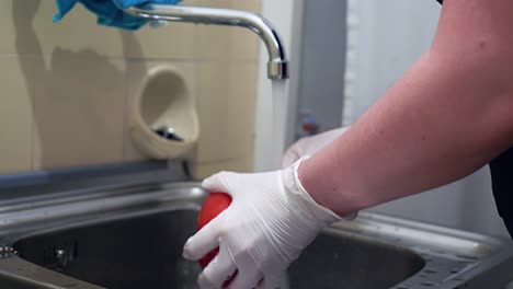 red paprika is washed under running water with disposable gloves