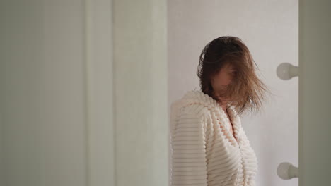 brunette woman listens to songs straightening wet hair after washing. cheerful woman moves to music in reflection of mirror in bathroom slow motion