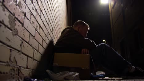a reflective moment in the shadows: capturing the solitude and struggles of an individual seeking shelter in an urban alleyway at night