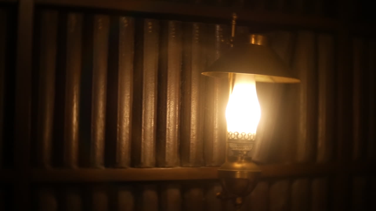 Uma lâmpada quente e brilhante projeta luz suave sobre fileiras de livros vintage em uma biblioteca ou espaço de estudo aconchegante e atmosférico, perfeito para cenas literárias ou ambientes de leitura serenos