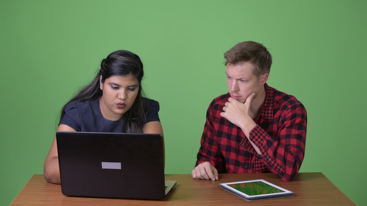 joven pareja de negocios multiétnica juntos contra un fondo verde