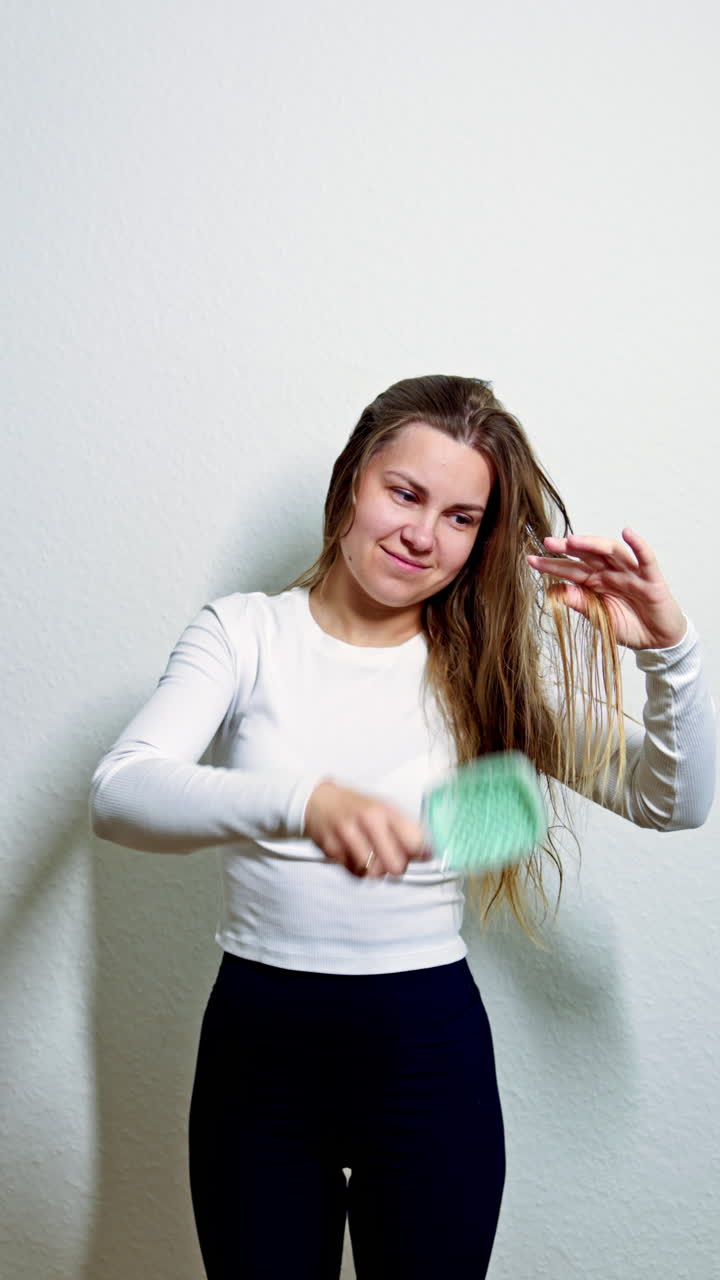 Cabello sano y hermoso después de procedimientos cosméticos. Mujer hermosa sonriendo peinándose el cabello largo y brillante con un peine por la mañana. Cuidado del cabello