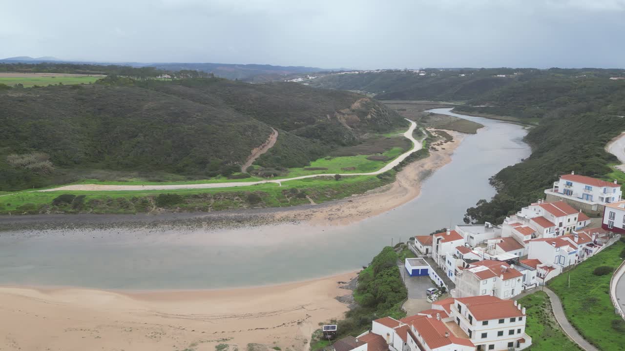 Serene aerial view of Aljezur, Portugal, showcasing the river, lush greenery, and coastal town