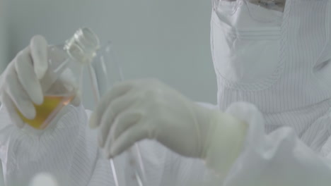 Research laboratory worker in lab coats wearing safety glasses studying biological experiment cell culture essay in sterile environment of designated biosafety biotechnology lab while using test tubes