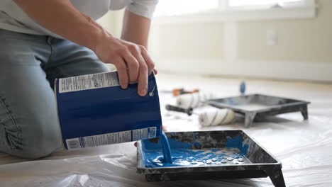 pouring blue paint into a paint tray