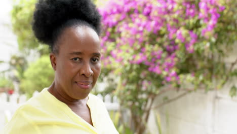 Happy-african-american-senior-woman-standing-and-smiling-in-sunny-garden,-slow-motion