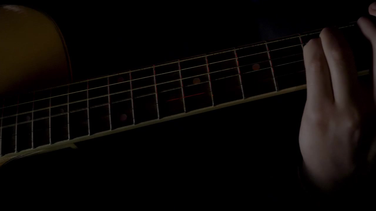 Close-up of an acoustic guitar in a dark setting