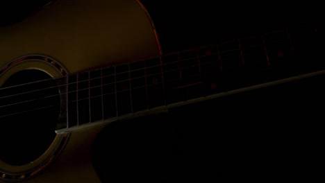 close-up of an acoustic guitar in a dark setting