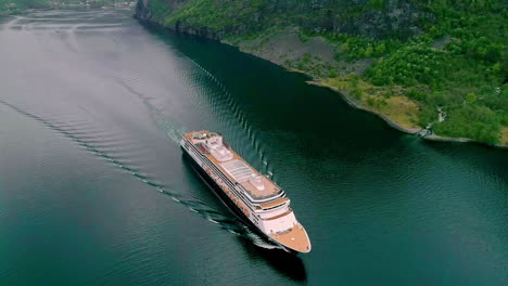 aerial drone bird's eye view over giant cruise ship in motion along norwegian fjord in flam, norway on a cloudy day