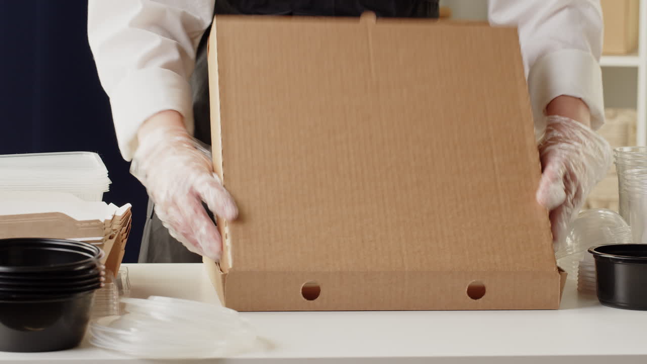 Person in Gloves Packaging Pizza Box for Takeaway Order