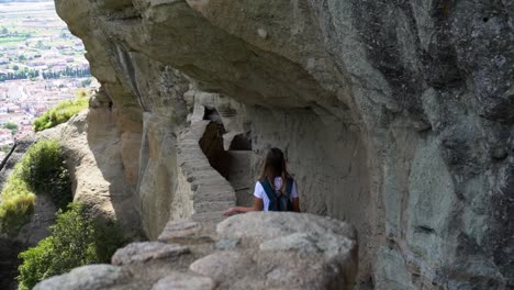 woman walks along a rocky path to a monastery