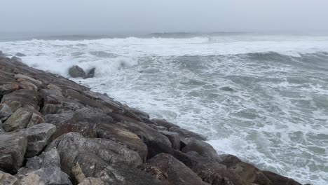 Light-waves-run-over-wave-breaker,-Furadouro-Atlantic-coast,-Portugal