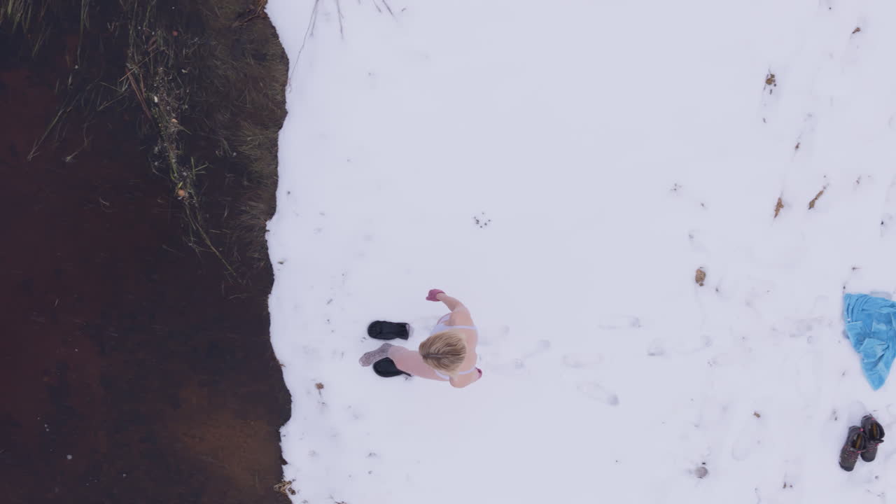 vista de un plan de una mujer bajo el agua entrando en el agua helada del lago para su inmersión de rutina