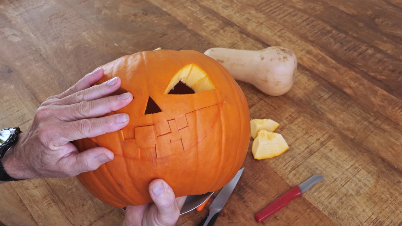 Carving scary face on pumpkin with knife during Halloween preparation
