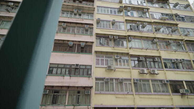 Reflexo da linha do horizonte de Hong Kong em janelas de um antigo edifício de apartamentos.