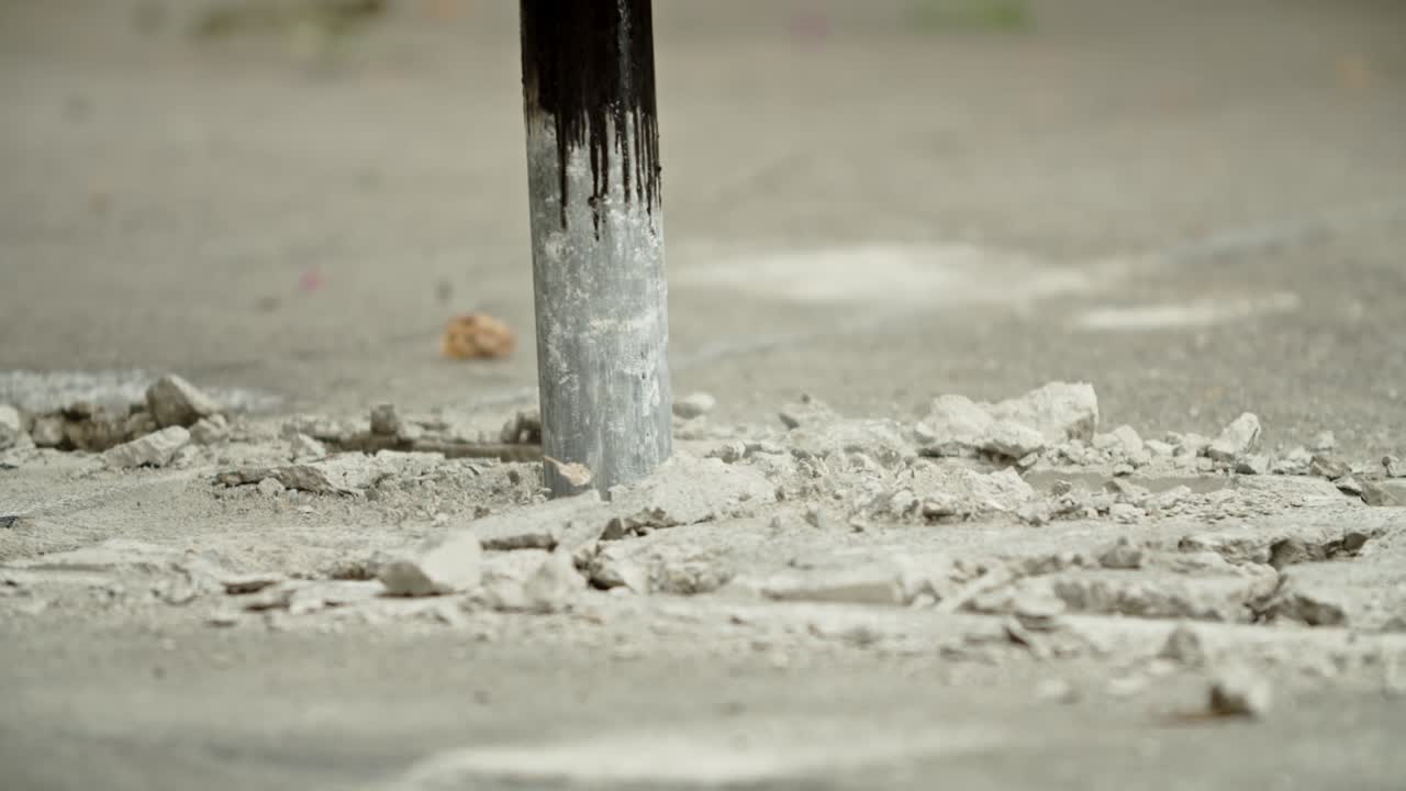 Close-up of excavator hydraulic arm rock breaker working on concrete road