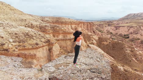 drone disparó a una joven hermosa mujer caucásica de pie en la cima de la montaña. turista usando teléfono inteligente para hacer selfies juntos en el punto de vista. disparo aéreo, naturaleza, viajes y concepto de aventura