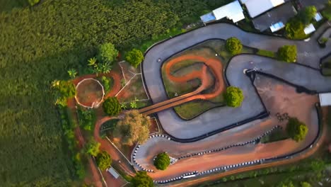 o drone 4k vira à direita após a corrida de kart em uma pista ao pôr do sol