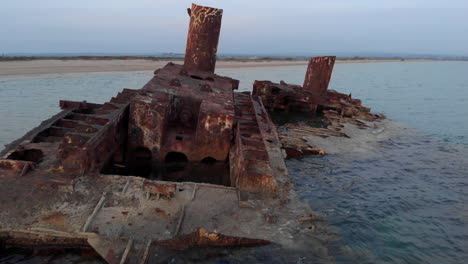 Drone-Video-passing-slowly-over-shipwreck-Blue-sea-waters-Sunset