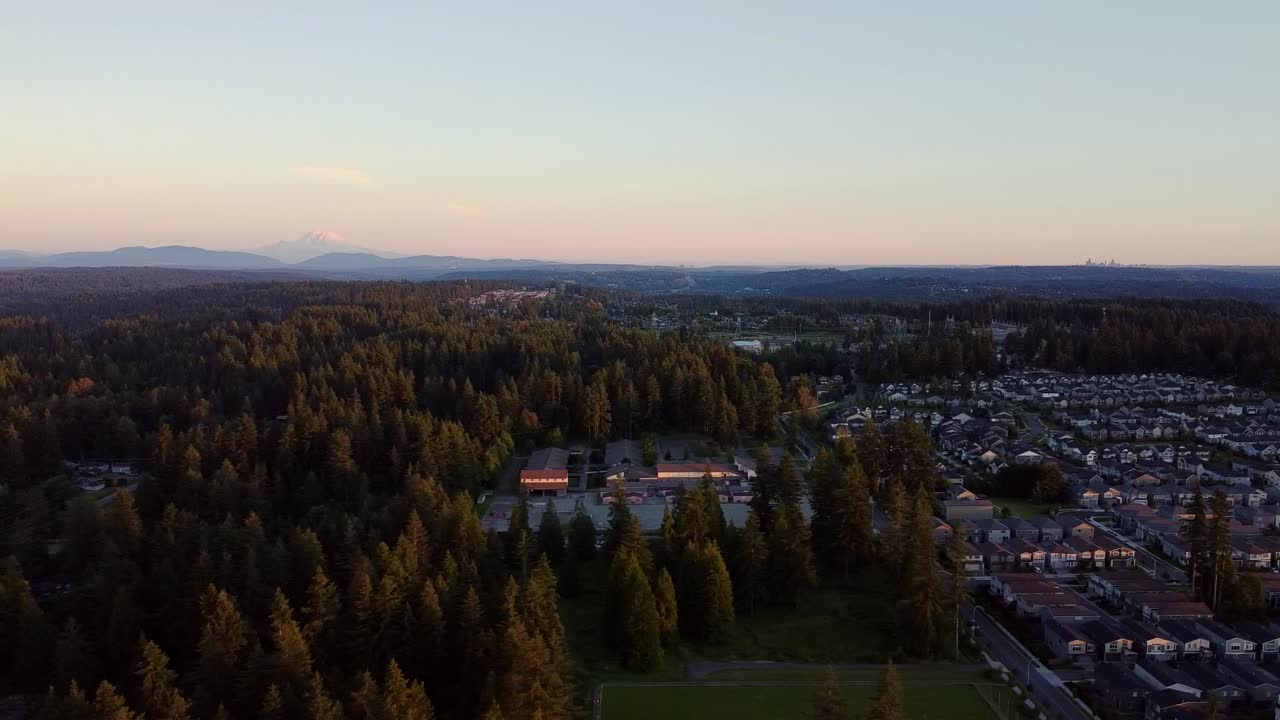 vista aérea de un barrio suburbano en el estado de washington al atardecer, mount rainer y seattle en el fondo