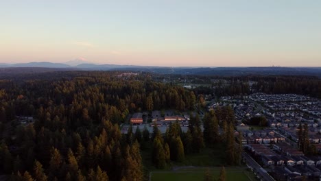 Aerial-view-of-suburban-neighborhood-in-Washington-State-at-sunset,-Mount-Rainer-and-Seattle-in-the-background