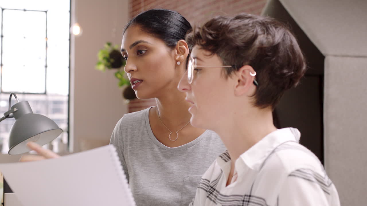 Two Women Discussing Documents in a Modern Office