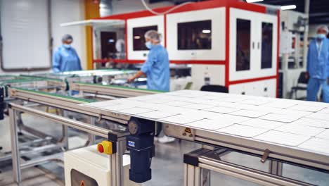 automated equipment inside the factory. new panel moving on conveyor line on the modern factory background. workers control the work of robotic equipment in the plant.