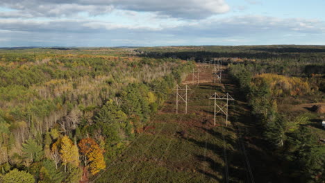 drone flyover shot of powerlines running through a forest in maine