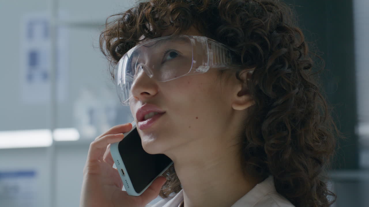 Young Woman in Safety Goggles Talking on Phone in Scientific Laboratory