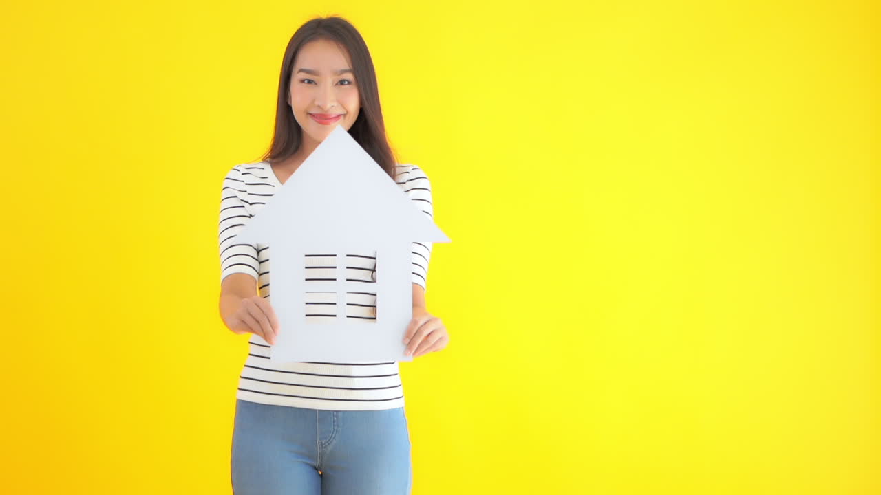 A young pretty Asian woman holds up a symbol of a house