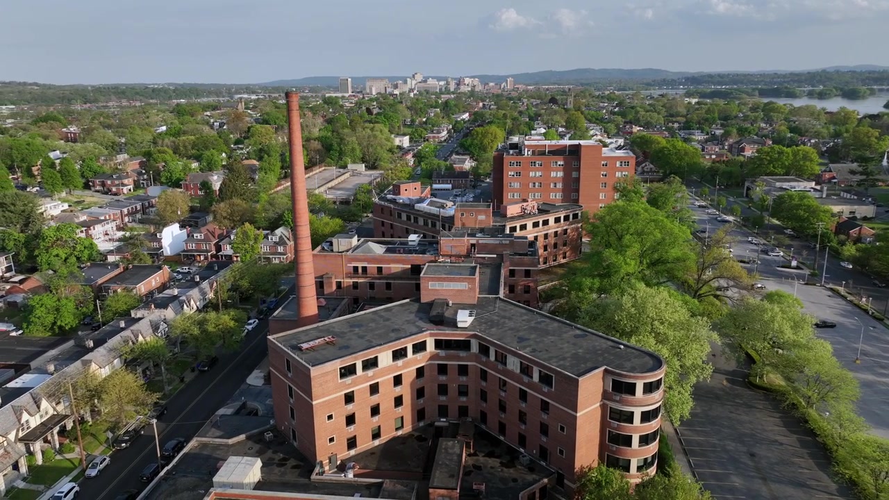 Historische Mehrfamilienhäuser mit roten Ziegelschornsteinen in einem amerikanischen Vorort. Innenstadt mit Skyline im Hintergrund. Weitwinkel-Orbit-Luftaufnahme.