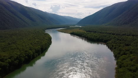 panoramic view of a river flowing through a forested mountain valley
