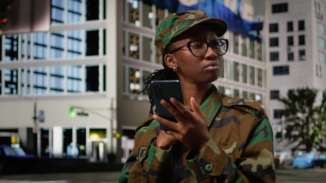 Soldato dell'esercito che cammina per una strada cittadina, consultando un'app di mappe sul suo smartphone.