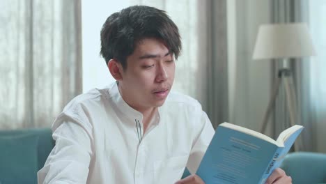 close up of asian man student being sleepy while reading a book at home