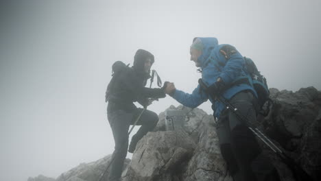 two hikers reached the top of mountain stol, congratulatin each other with a hand shake