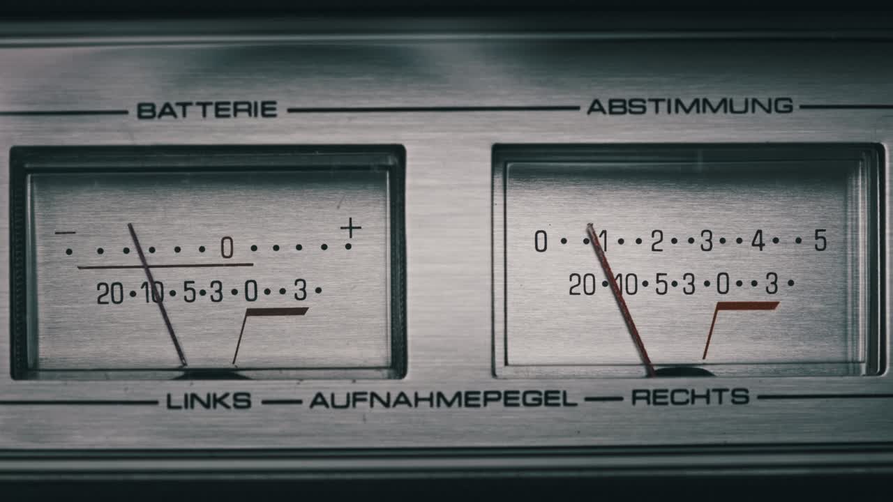 dos medidores de vu analógicos en una grabadora de cinta de color plateado, indicadores de flecha