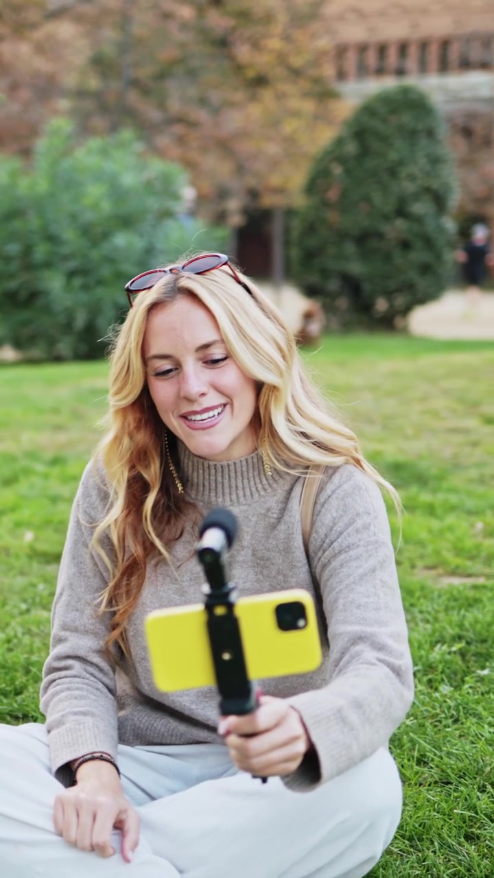 Giovane donna allegra che fa vlogging sull'erba nel parco