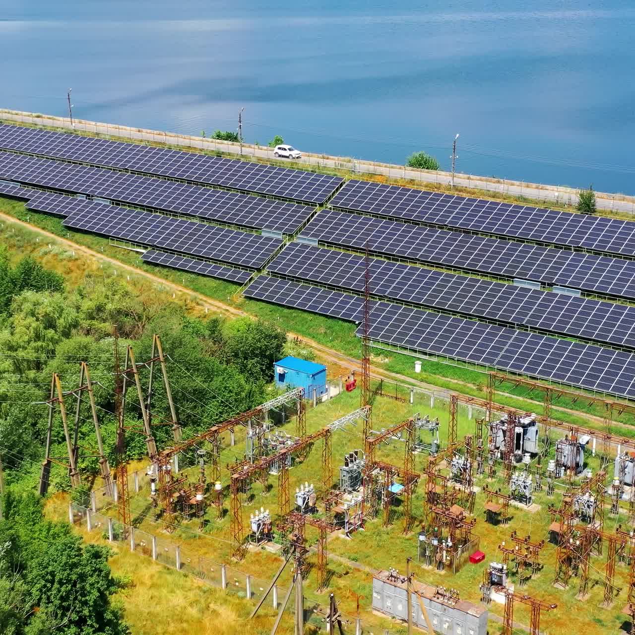 Solar power station near river at sunny day. Some solar panels in rows for power Production. Renewable green energy. Alternative energy sources. Top aerial view