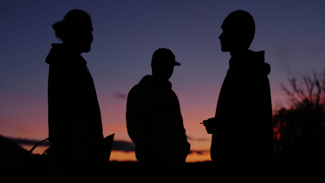 젊은 남성들의 그룹은 마법의 파란 시간 조명, 담배를 피우고 채팅에 서 있습니다.