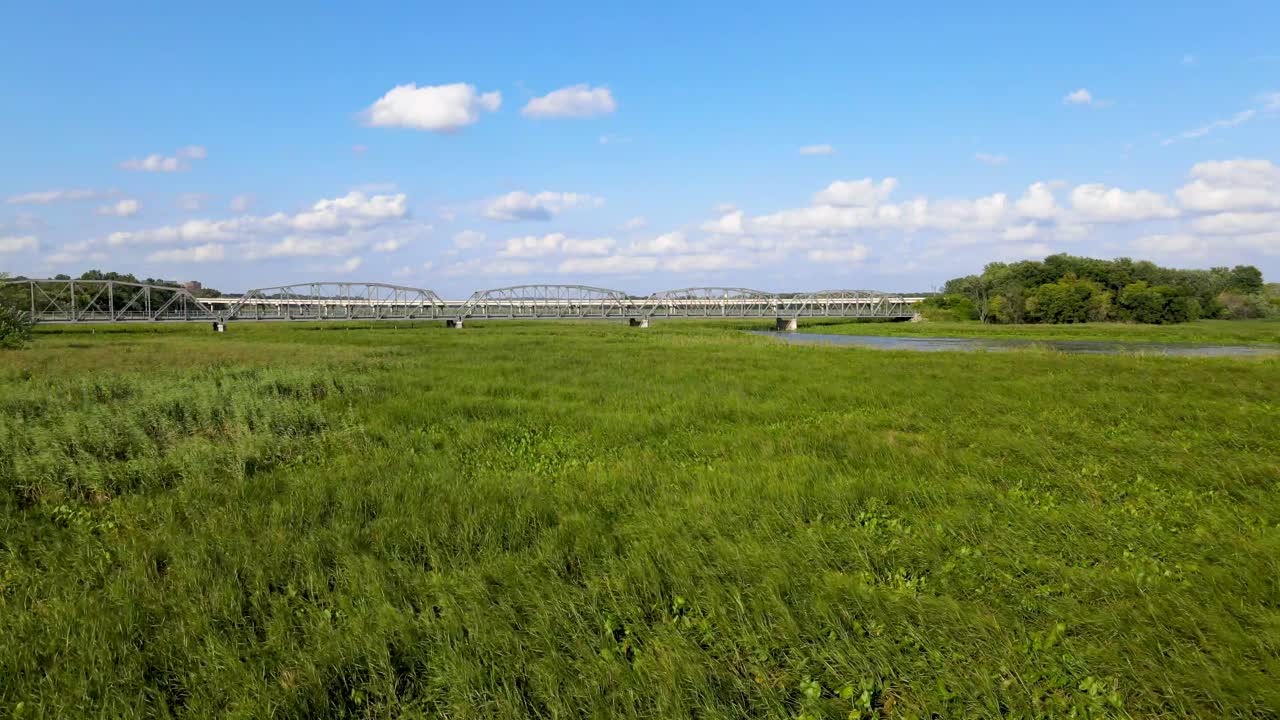 미네소타 주 블루밍턴의 아름다운 오래된 세더 애비뉴 다리를 향해 날아가는 드론과 함께 자전거를 타고 다리를 건너고 있습니다.