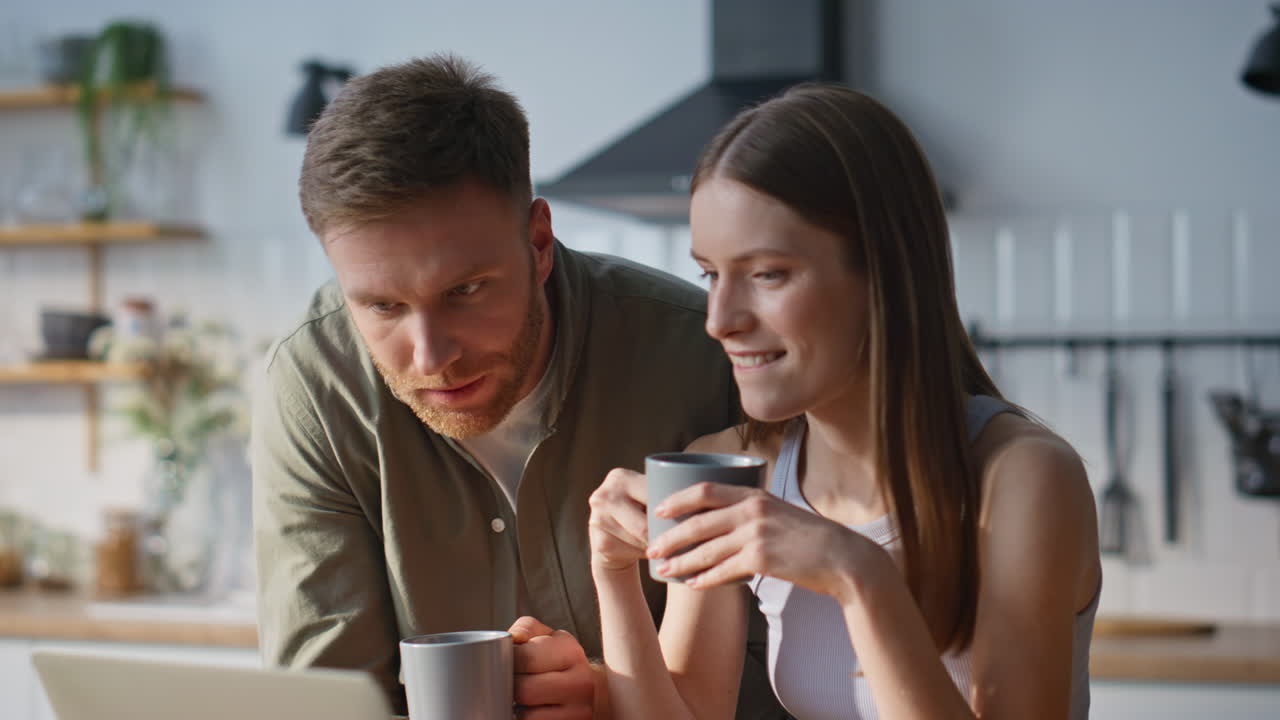 Family couple looking laptop in kitchen holding coffee closeup. Relaxed spouses