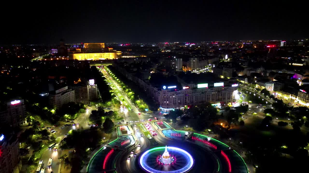 Panoramic aerial viewo fo city center of Bucharest at night. View of Water Fountain illuminated. POanoramic viewo of all old town center. Palace of the Parliament building in background. Drone forward
