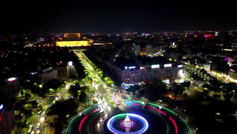 panoramic aerial viewo fo city center of bucharest at night. view of water fountain illuminated. poanoramic viewo of all old town center. palace of the parliament building in background. drone forward