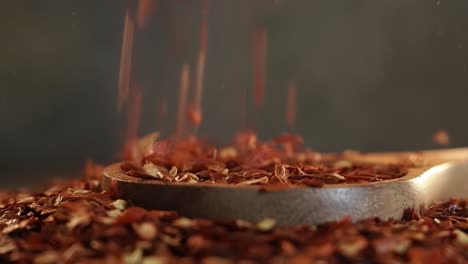 Flakes-of-red-hot-chili-pepper-in-wooden-spoon-closeup-on-a-kitchen-table.