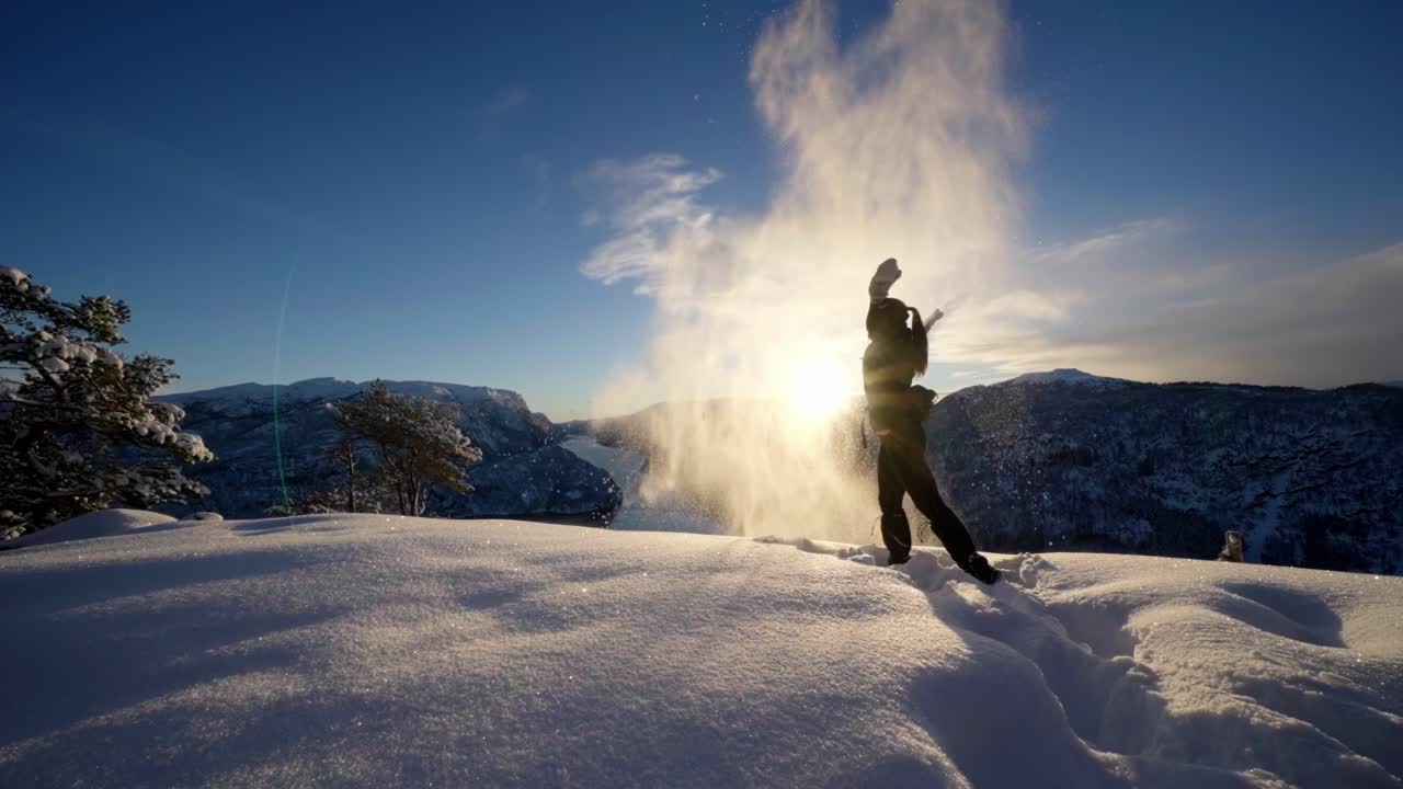 Donna crea un magico spettacolo di neve, lanciando la neve in aria al rallentatore.