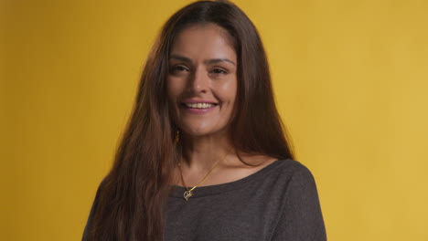 Retrato-De-Estudio-De-Cabeza-Y-Hombros-De-Una-Mujer-Sonriente-Contra-Un-Fondo-Amarillo